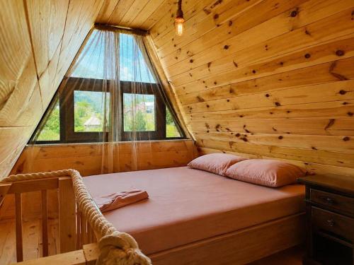 a bed in a log cabin with a window at Konak in Podgorica