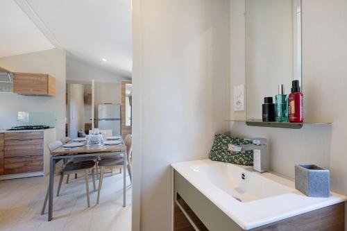 a kitchen with a white sink and a table at Mobilehome Evasion 55 in Saint-Gervais