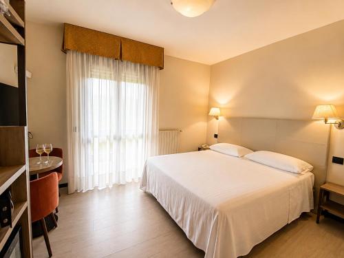 a hotel room with a white bed and a window at Hotel Parigi 2 & Spa in Dalmine