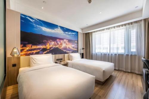 two beds in a hotel room with a painting on the wall at Atour Hotel Shuangyong Ave in Yan'an