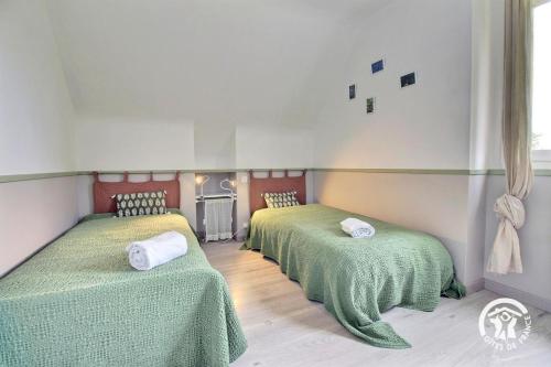 a room with three beds with green blankets at Ar gwelva in Cléguérec