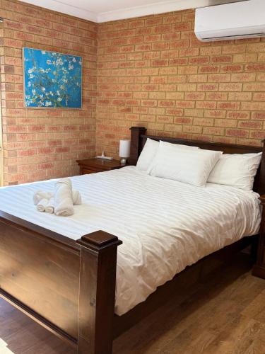 a bedroom with a large bed with a brick wall at Corner unit in Geraldton in Geraldton