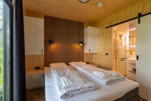 a bedroom with a bed with white sheets and a tub at Zicht op Twente - Spa lodges in Markelo