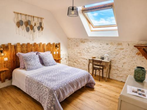 a bedroom with a bed and a desk and a window at Le pré de la rue in Bouesse