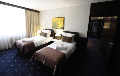a hotel room with two beds and a window at Hotel Holiday in Sarajevo