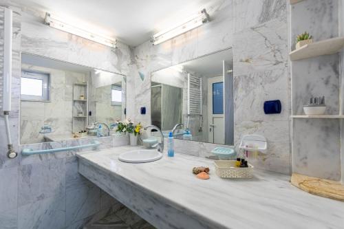 a bathroom with a sink and a large mirror at Paco's Resort Standard Studio 2 in Oziás