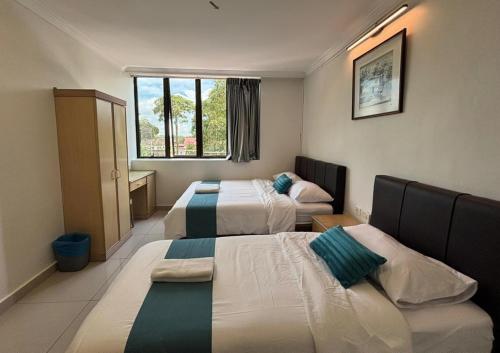 a hotel room with three beds and a window at Wangsa Village Inn in Ulu Tiram