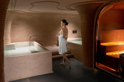 a woman is standing in a bath tub at KiN Hotel Onsen in Ho Chi Minh City