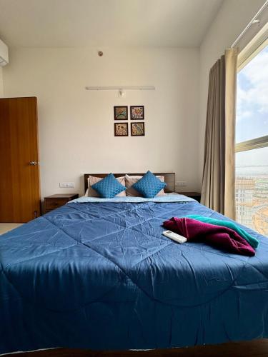 a bedroom with a blue bed with a window at Sky height 2BHK in GIFT CITY in Gandhinagar