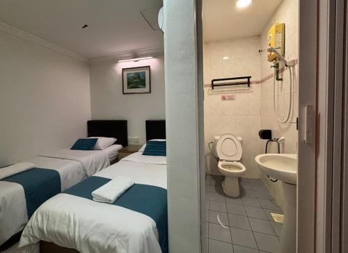 a hospital room with three beds and a sink at Wangsa Village Inn in Ulu Tiram