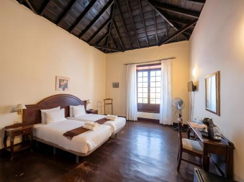 a bedroom with a bed and a desk and a window at Tamahuche Hotel Rural in Vallehermoso