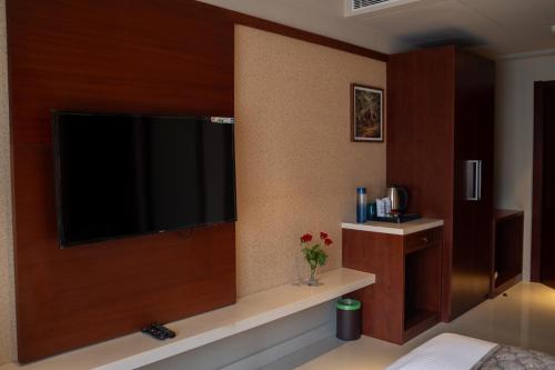 a bedroom with a large flat screen tv on a wall at Luxo Wayanad in Sultan Bathery