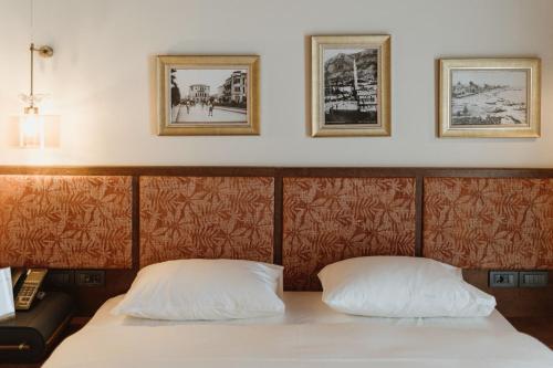 a bed with two pillows and two pictures on the wall at The Noria Hotel in Arsuz