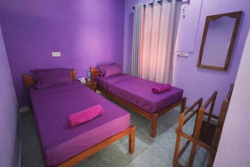 a purple room with two beds and a mirror at East Breeze in Arugam Bay