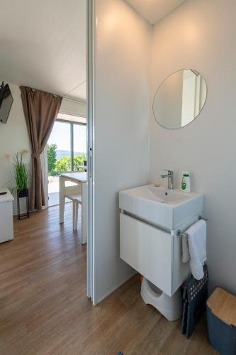 a white bathroom with a sink and a mirror at Vela Stina Mobile home in Roč