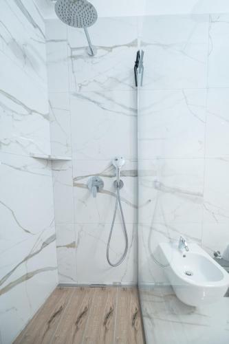 a white bathroom with a shower and a sink at Studio apartma Kamin in Nova Vas