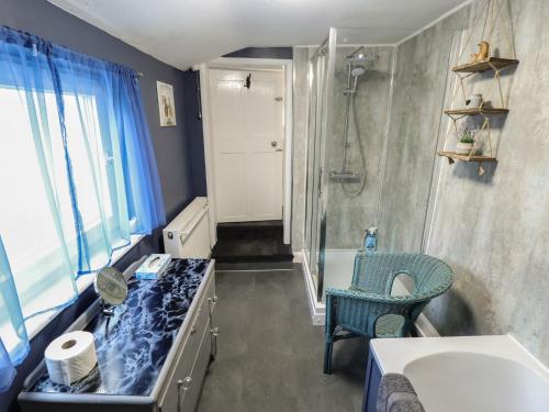 a bathroom with a shower and a blue chair at Pankhurst Cottage in Louth