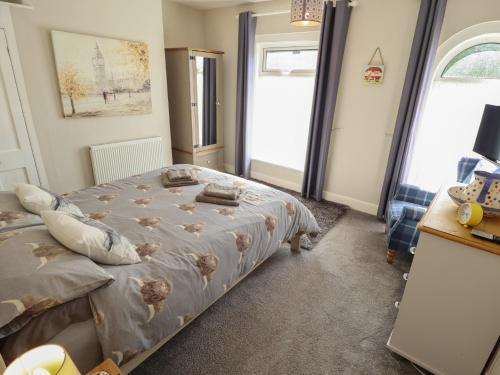 a bedroom with a bed and two windows at Pankhurst Cottage in Louth