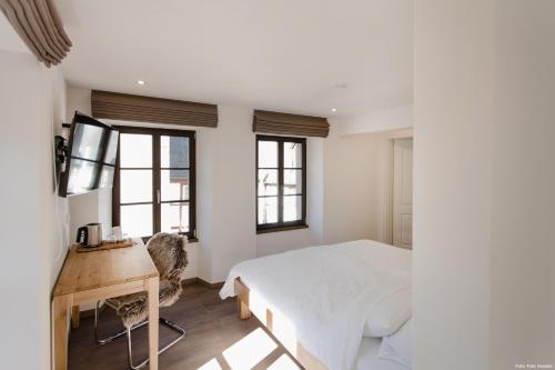 a bedroom with a bed and a desk and windows at Haus Auf der Zinn in Beilstein