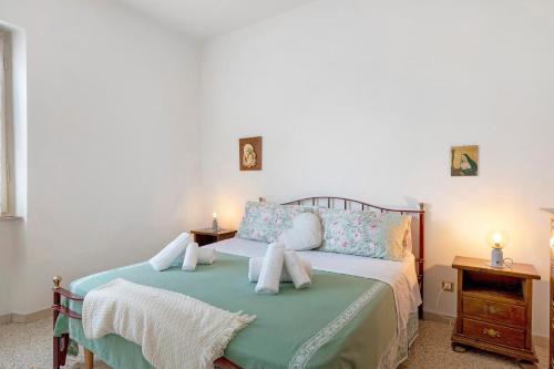 a bedroom with a bed with green sheets and pillows at Casa Ortensia in Spoleto