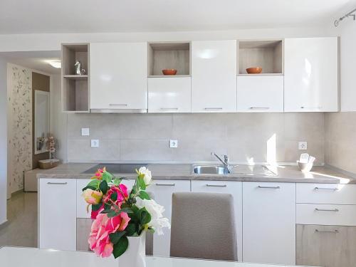 a kitchen with white cabinets and a vase of flowers at Apartments Gorica 2 in Baška
