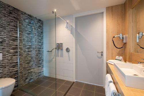 een badkamer met een douche, een toilet en een wastafel bij Hotel 46 in Wintelre