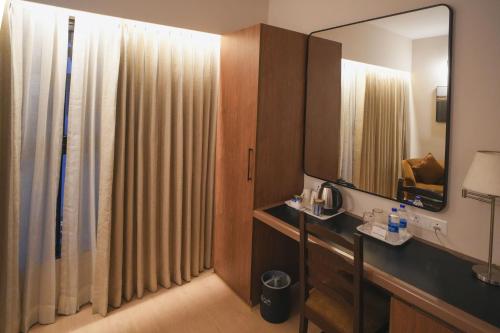 a bathroom with a vanity and a mirror and a sink at Hotel Park Central Koregaon Park in Pune