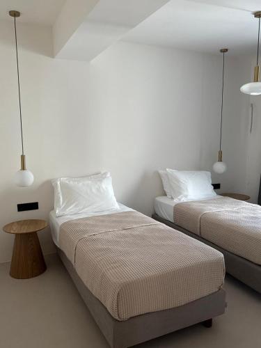 ein Schlafzimmer mit zwei Betten, einem Tisch und zwei Lampen in der Unterkunft Merichas Luxurious Villa in Kythnos