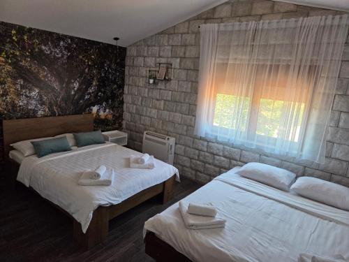 a bedroom with two beds and a window at Apartmani Drijen in Ravno