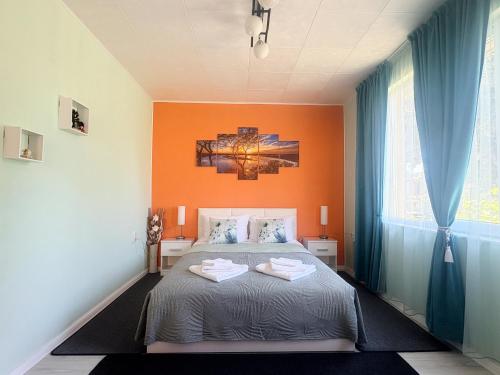 a bedroom with a bed with an orange wall at Velonia Guest House in Sozopol