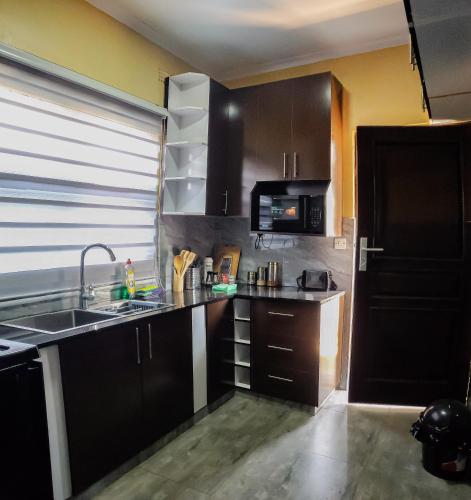 a kitchen with black cabinets and a sink and a microwave at Area 46 BnB in Lilongwe