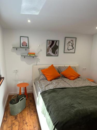 a bedroom with a bed with orange pillows and a stool at Kamińsko 640 - Puszcza Zielonka in Kamińsko