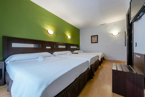 three beds in a room with a green wall at Sercotel Las Estrellas in Ciempozuelos