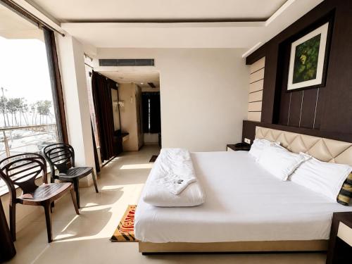 a bedroom with a bed and two chairs and a window at Hotel Big Boss New Digha in Digha