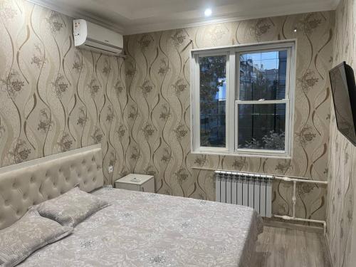 a bedroom with a bed and a window at Kvartira in Toshkent-Passajir Bekati