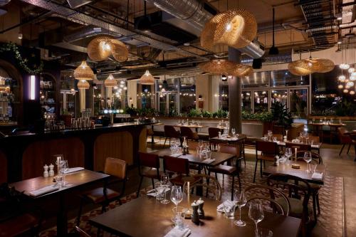 a restaurant with tables and chairs and chandeliers at Turing Locke Cambridge in Cambridge