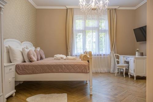a bedroom with a bed and a desk and a chandelier at Chillinn La Maison Cottage Eger in Eger