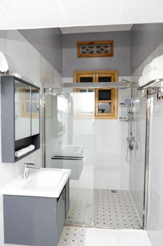 a white bathroom with a sink and a shower at MIRAMAR Ruhondo Resort in Muhororo