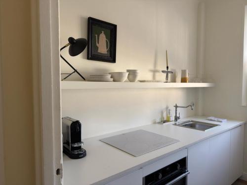a white kitchen with a sink and a lamp at Superbe Appartement ultra-centre climatisé in Vernon