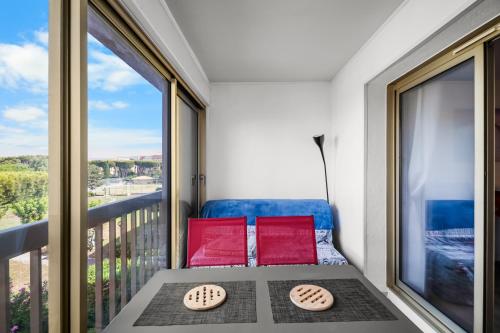 a balcony with two red cushioned chairs and a large window at T2 dans résidence arborée in Six-Fours-les-Plages