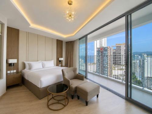 a bedroom with a bed and a chair and large windows at Handy Panorama Nha Trang in Nha Trang