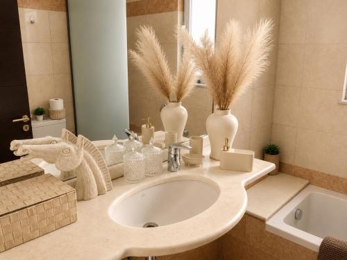 a bathroom with a sink with vases and a mirror at Phos & Kipos Villa in Koskinou