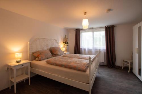 a bedroom with a white bed with two lamps and a window at Ferienwohnung Auerhahn in Lauterbach