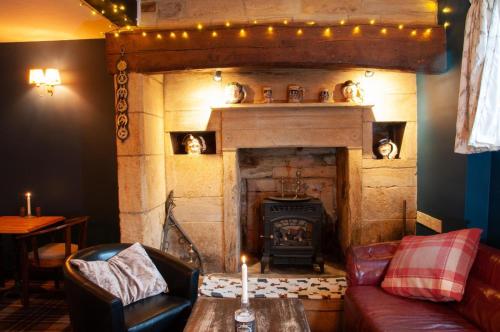 a living room with a fireplace with a couch and a table at Mason's Arms in Montacute