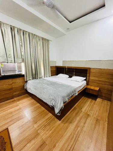 a bedroom with a bed with wooden floors and a window at Hari Kamal Invitation in Mathura