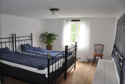 a bedroom with a bed with blue sheets and a window at Grönhagen in Loftahammar