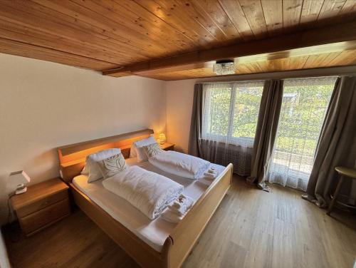 a bedroom with two beds and a large window at Hotel Milan - Self Check-In in Ringgenberg