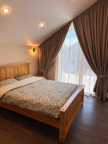a bedroom with a bed and a large window at Riverside Cottage in Palanga