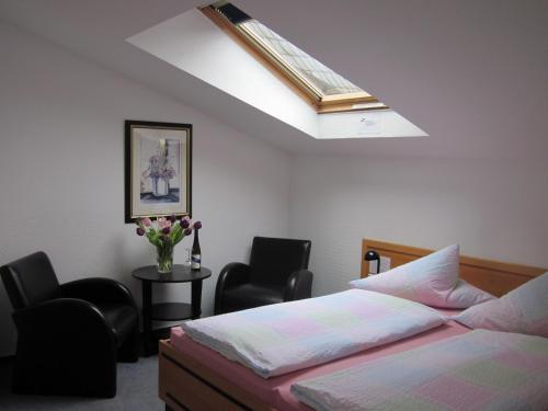 a bedroom with a bed and two chairs and a skylight at Hotel Anlage Heidelberg in Heidelberg