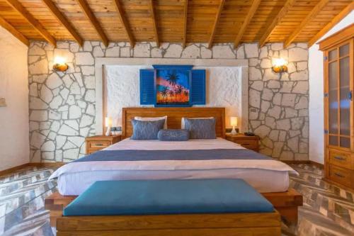 a bedroom with a king sized bed in a stone wall at Adella Garden Marina Hotel in Güvercin Adası